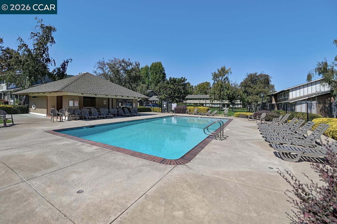 Community swimming pool with brick edging, rows of lounge chairs, and a covered pavilion.