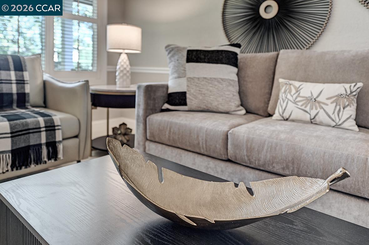 Staged living room with a gray sofa, plaid armchair throw, and sculptural bowl on the coffee table.