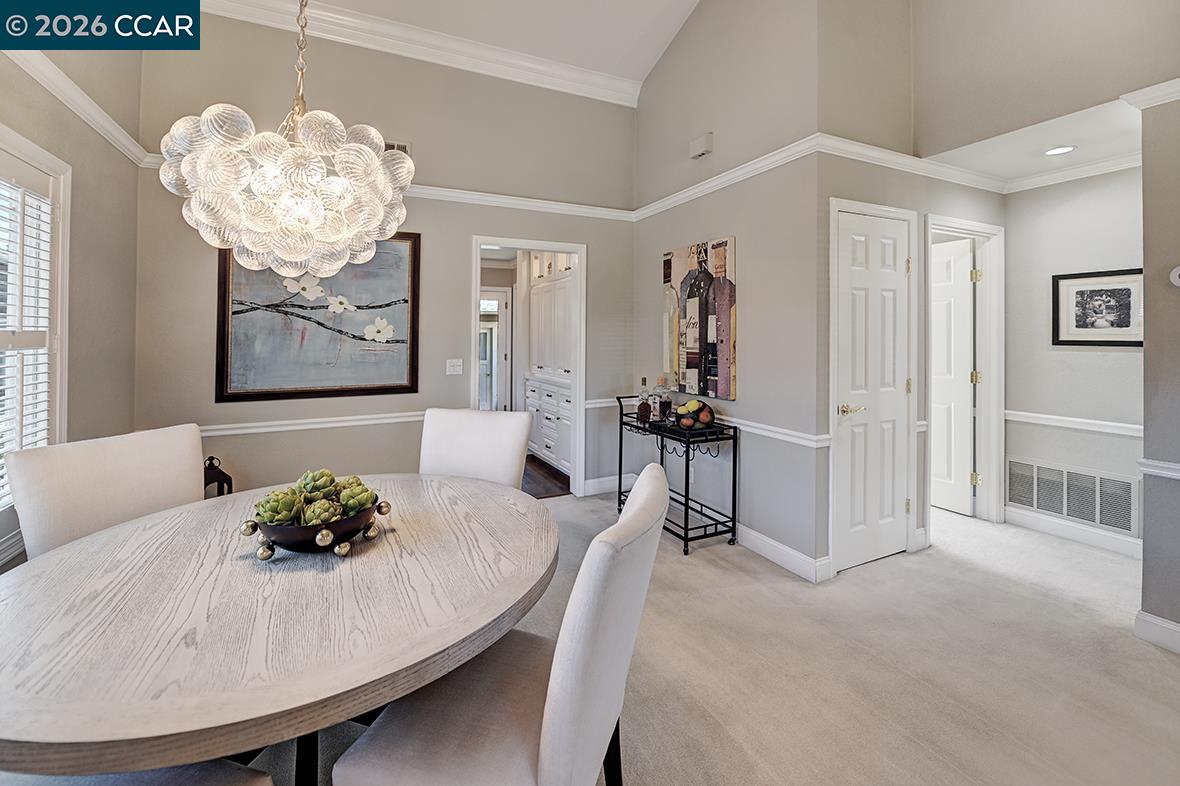 Dining room with a round pale wood table and a sculptural chandelier.