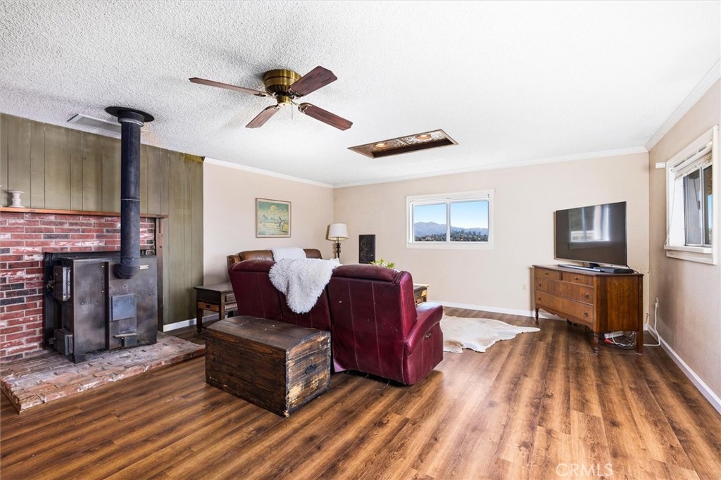 Living room with a brick fireplace, burgundy leather seating, wood floors, and mountain views.