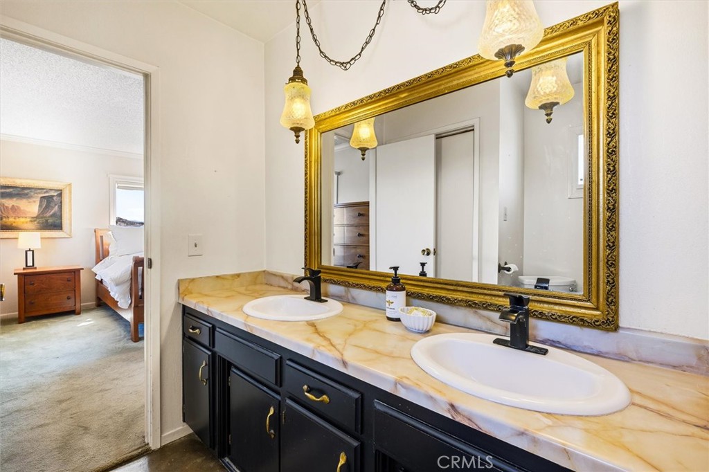 Bathroom with a double-sink vanity, black cabinetry, and an ornate gold-framed mirror.