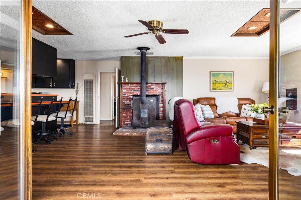 Open-plan living room with a brick fireplace, black wood stove, leather seating, and adjoining kitchen.
