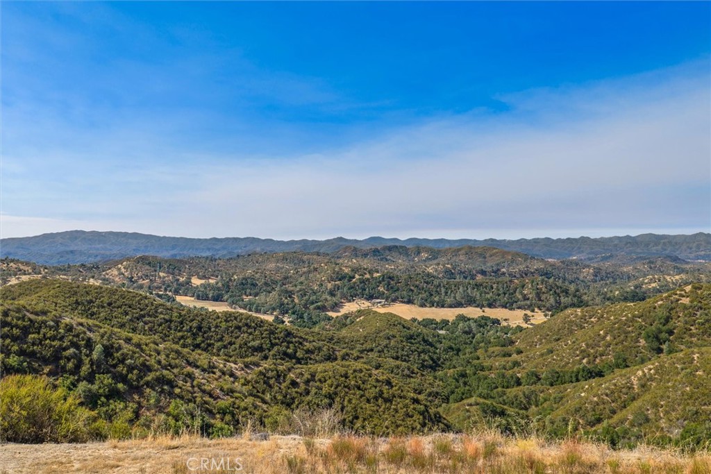 Rolling hills and a broad valley stretch toward distant mountain ridges.