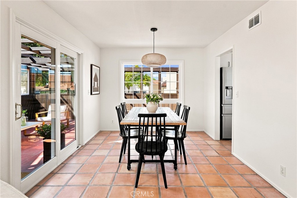Dining room with a wood table, terracotta tile floor, and sliding glass doors to a patio.