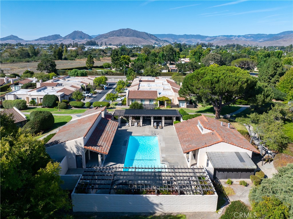 Aerial view of a swimming pool and homes with mountains in the distance.