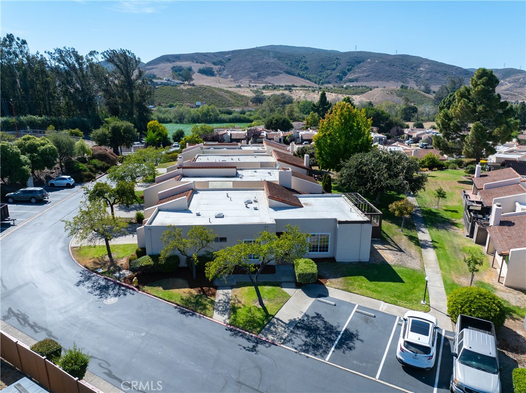 Aerial view of a low-rise property with flat roofs and parking, with hills in the background.
