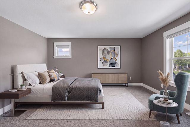 Staged bedroom with gray bedding, a wood-front dresser, and a teal chair beside the window.
