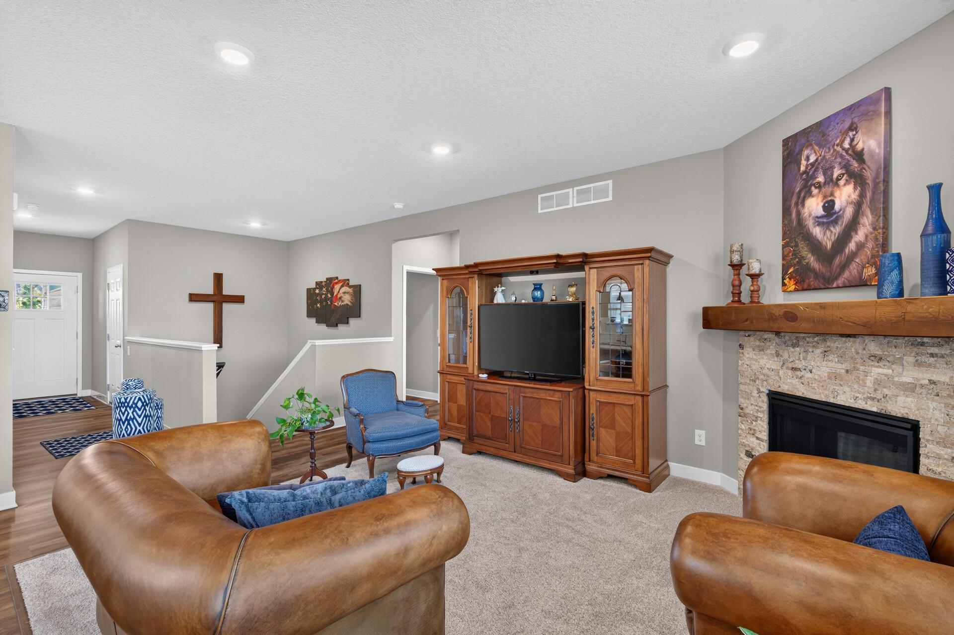 Living room with leather sofas, a wooden TV cabinet, and a stone fireplace.