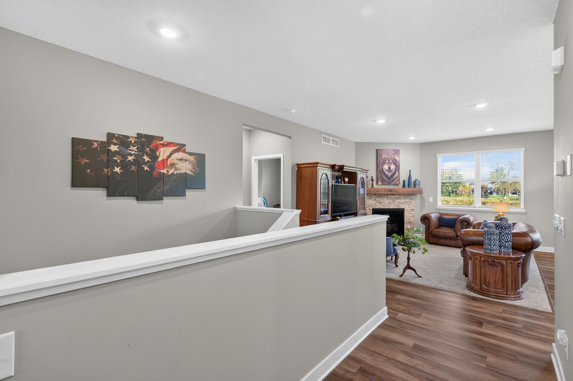 Furnished living room with a stone fireplace, leather seating, and large windows.