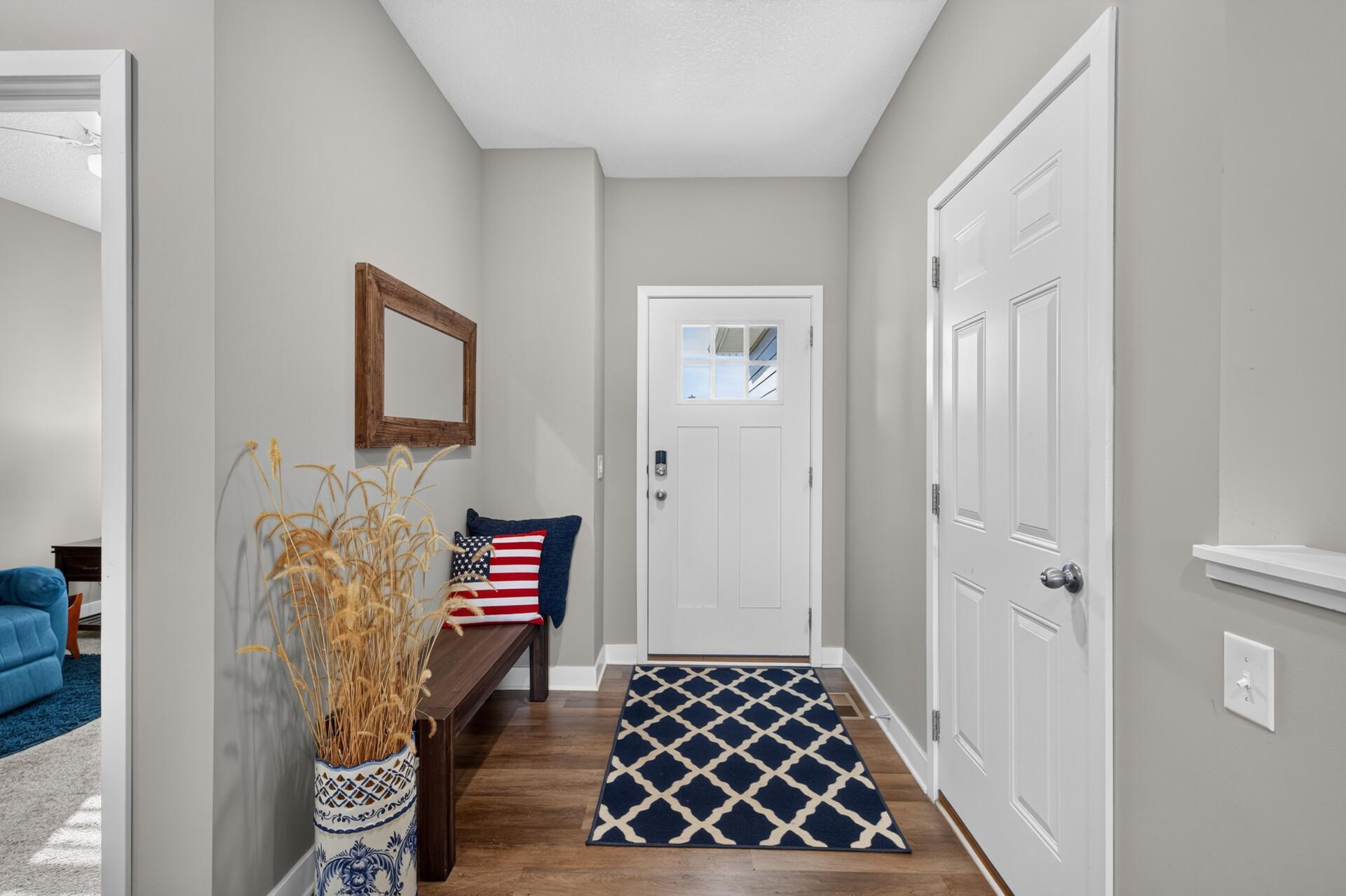 Entryway with a white front door, patterned navy runner, and decorated wood console