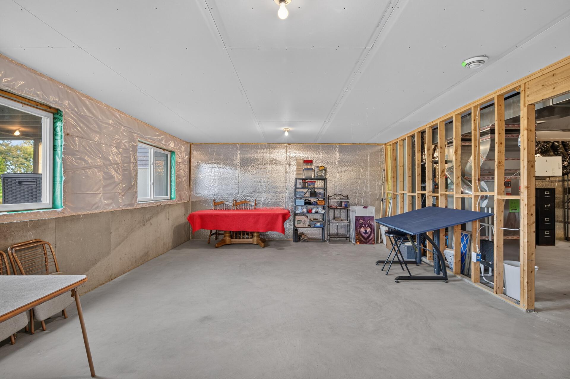 Unfinished basement with concrete floors, exposed framing, and HVAC equipment along one wall.