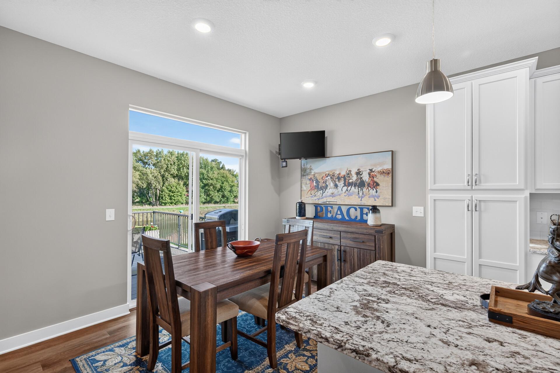 Dining area with dark wood table beside white kitchen cabinetry and a sliding glass door to the deck.