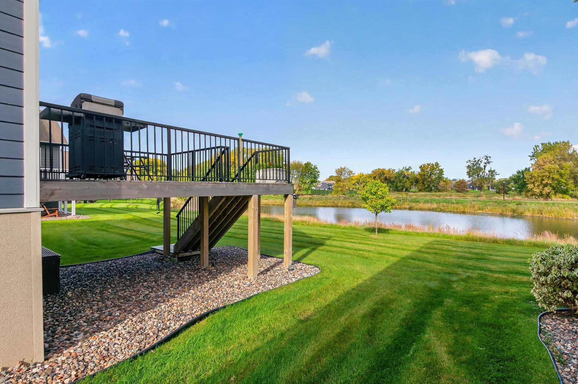 Raised deck overlooks a pond and neatly mowed lawn.