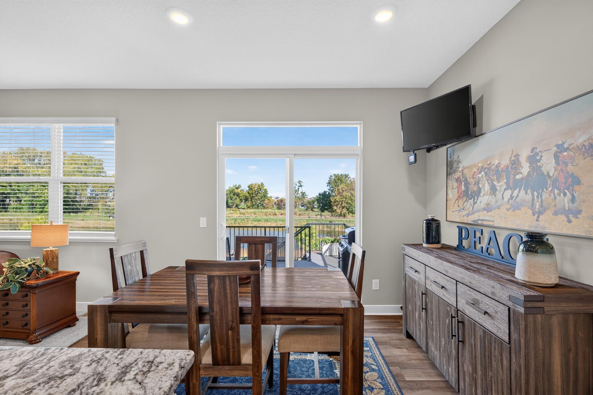 Dining room with a dark wood table, sliding doors, and a deck overlooking water.