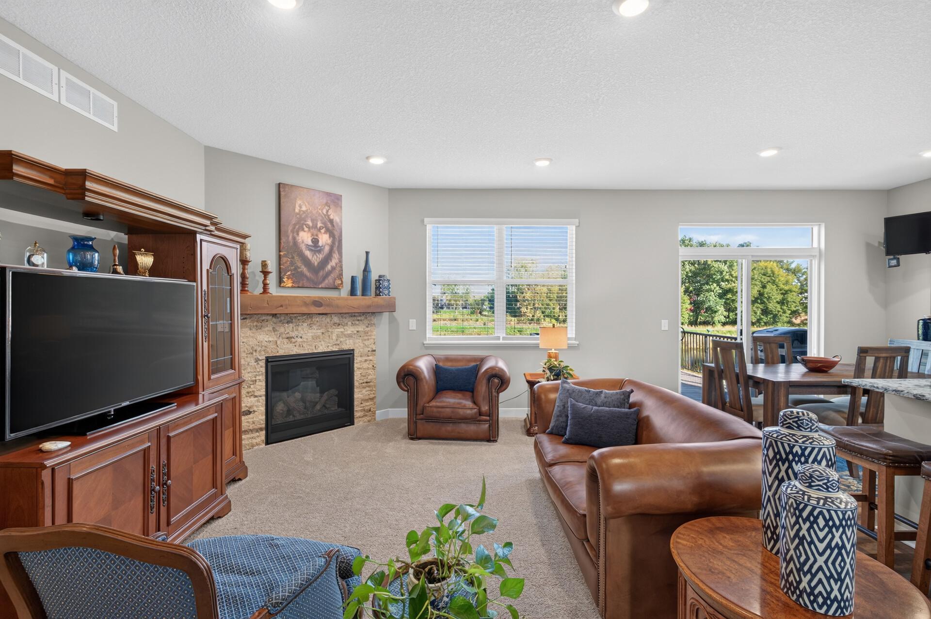 Living room with a stone fireplace, built-in television cabinet, leather seating, and adjoining dining area.