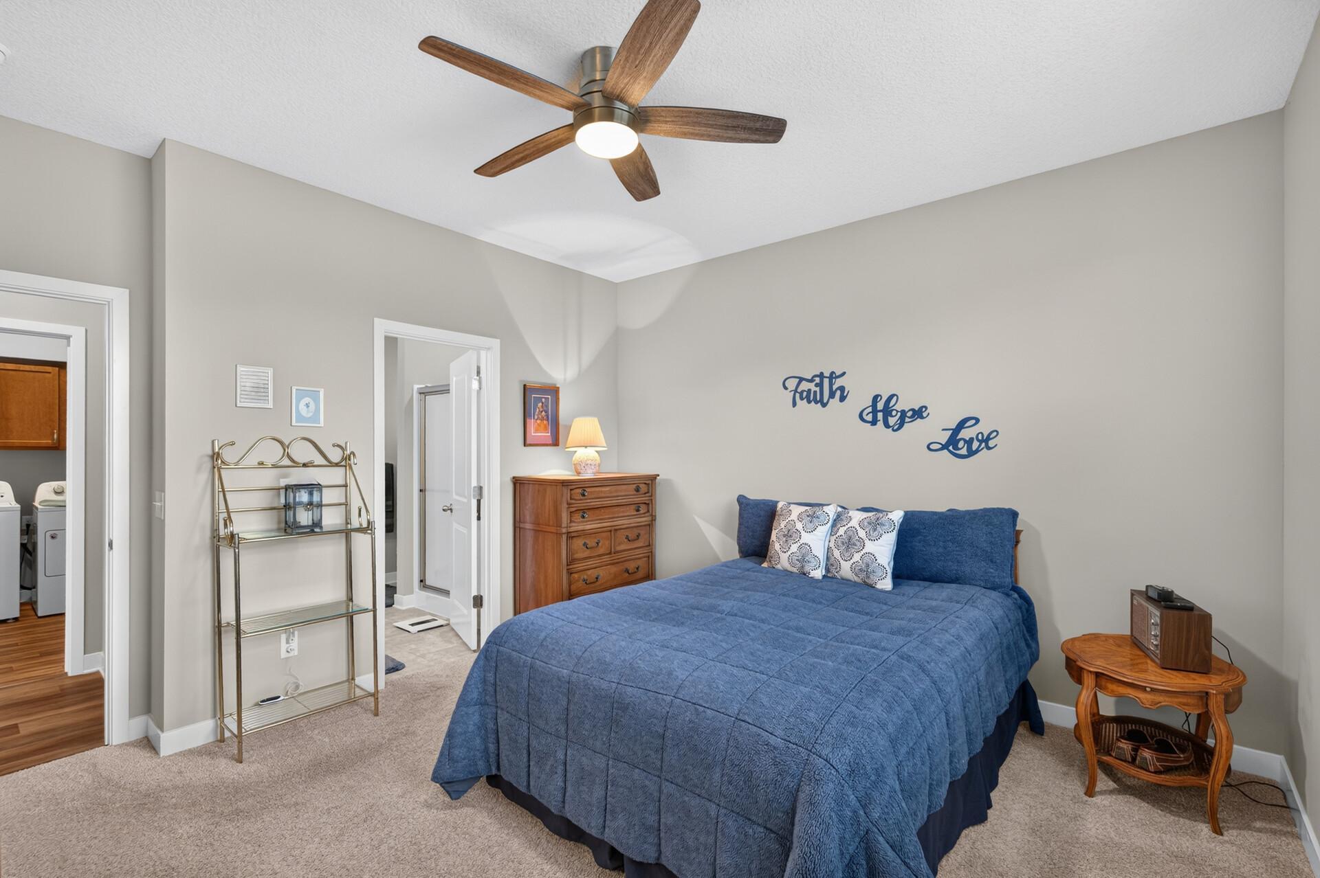 Bedroom with a blue bed, wood dresser, and “Faith Hope Love” lettering on the wall.