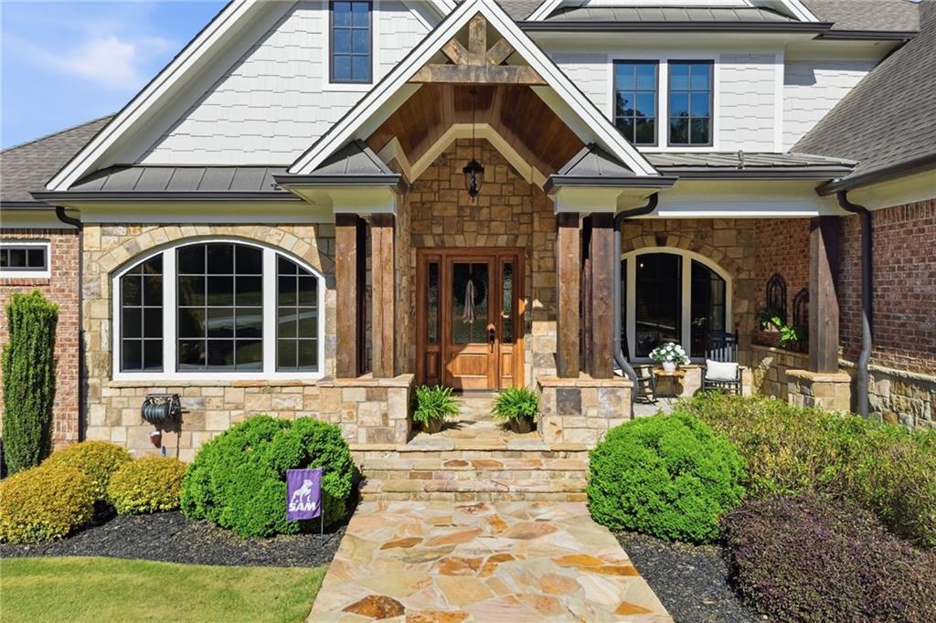 Two-story home with a stone entry, arched windows, and a landscaped walkway.