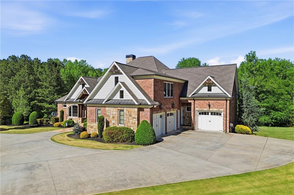 Large brick-and-stone home with white-trimmed gables and a broad concrete driveway.