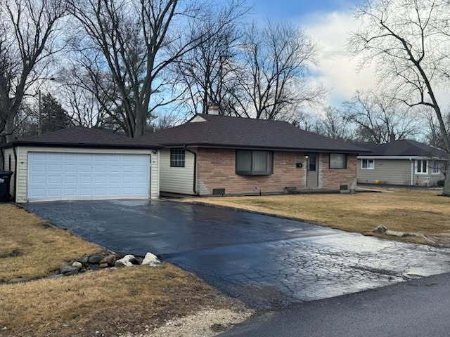 Single-story brick ranch home with an attached two-car garage and wet driveway.