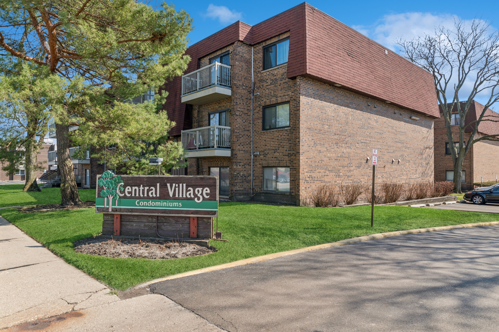 Brick condominium building with balconies behind the Central Village Condominiums sign.