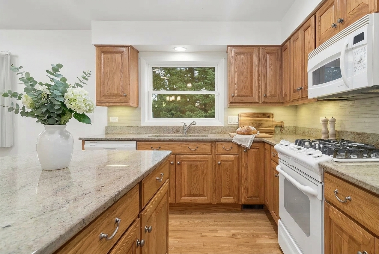 Kitchen with oak cabinets, granite counters, and a window above the sink.