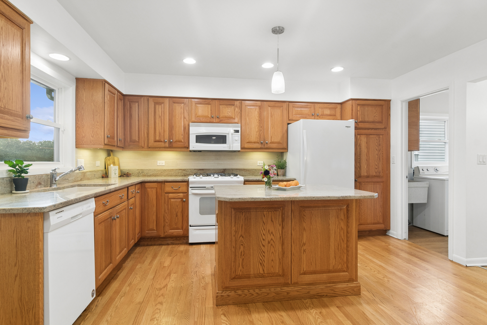 Kitchen with oak cabinetry, granite counters, a central island, and hardwood floors.