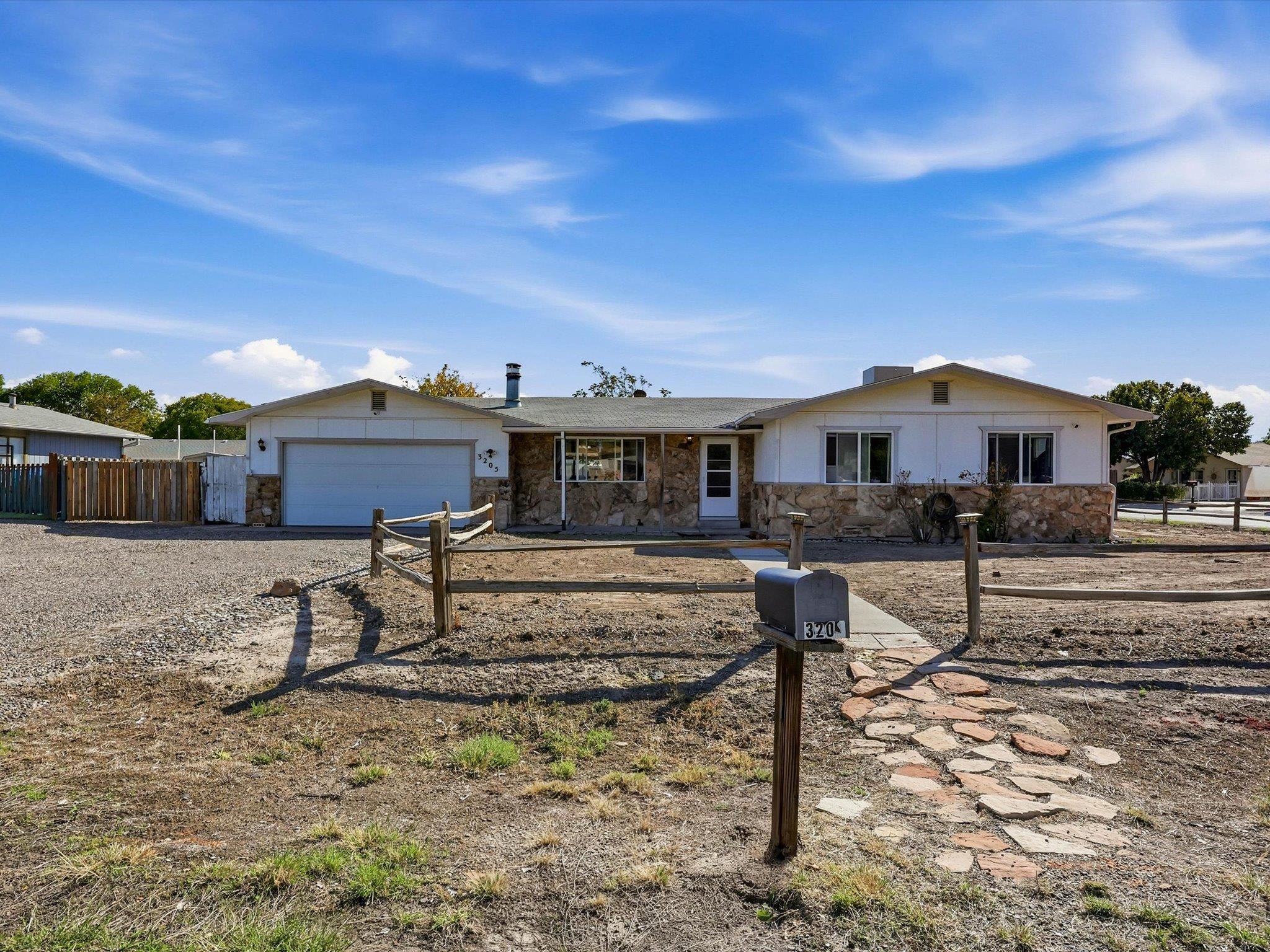 Single-story ranch home with stone facade, attached garage, gravel yard, and mailbox marked 3205.