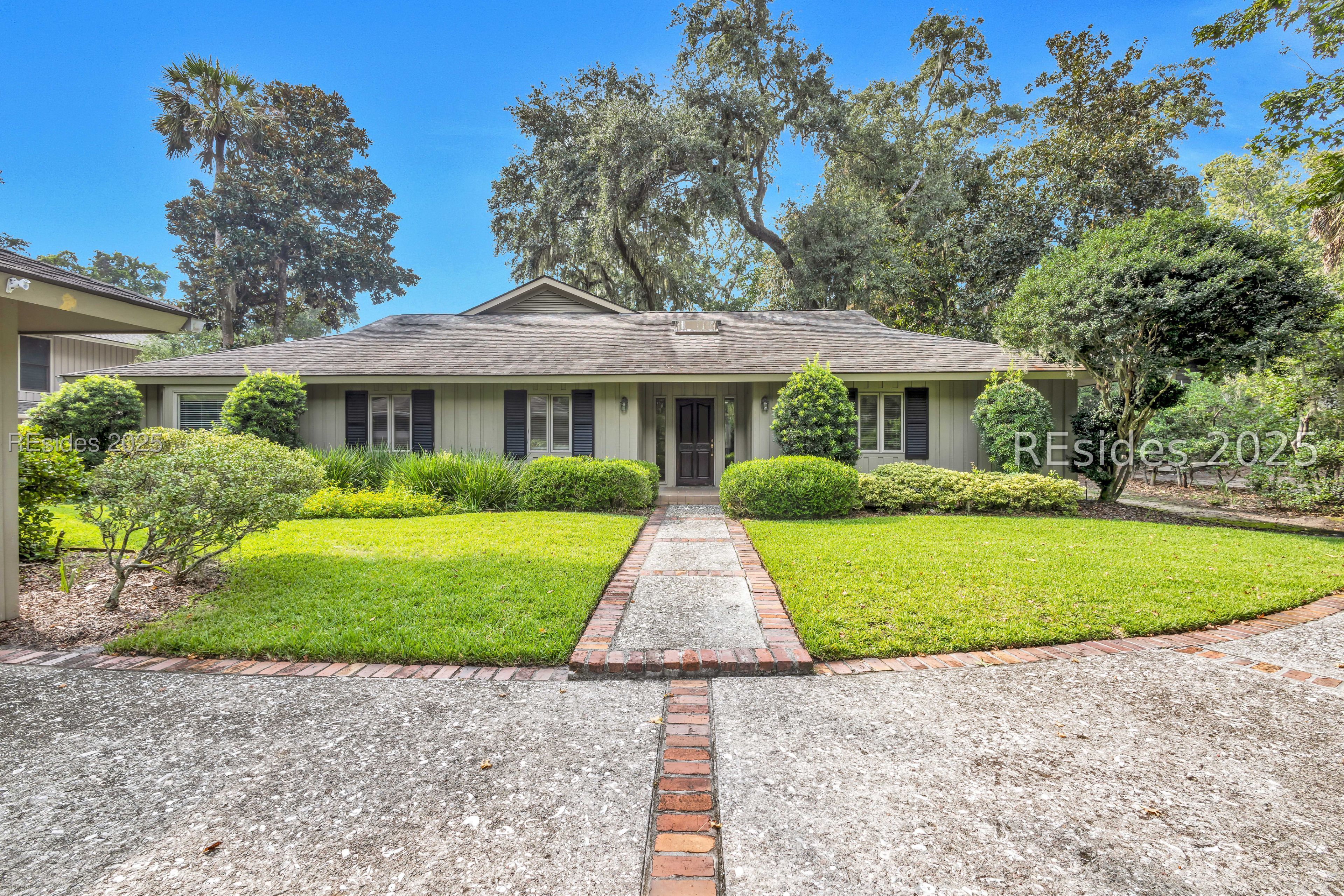 Single-story home with landscaped lawn and brick-edged walkway leading to the front door.