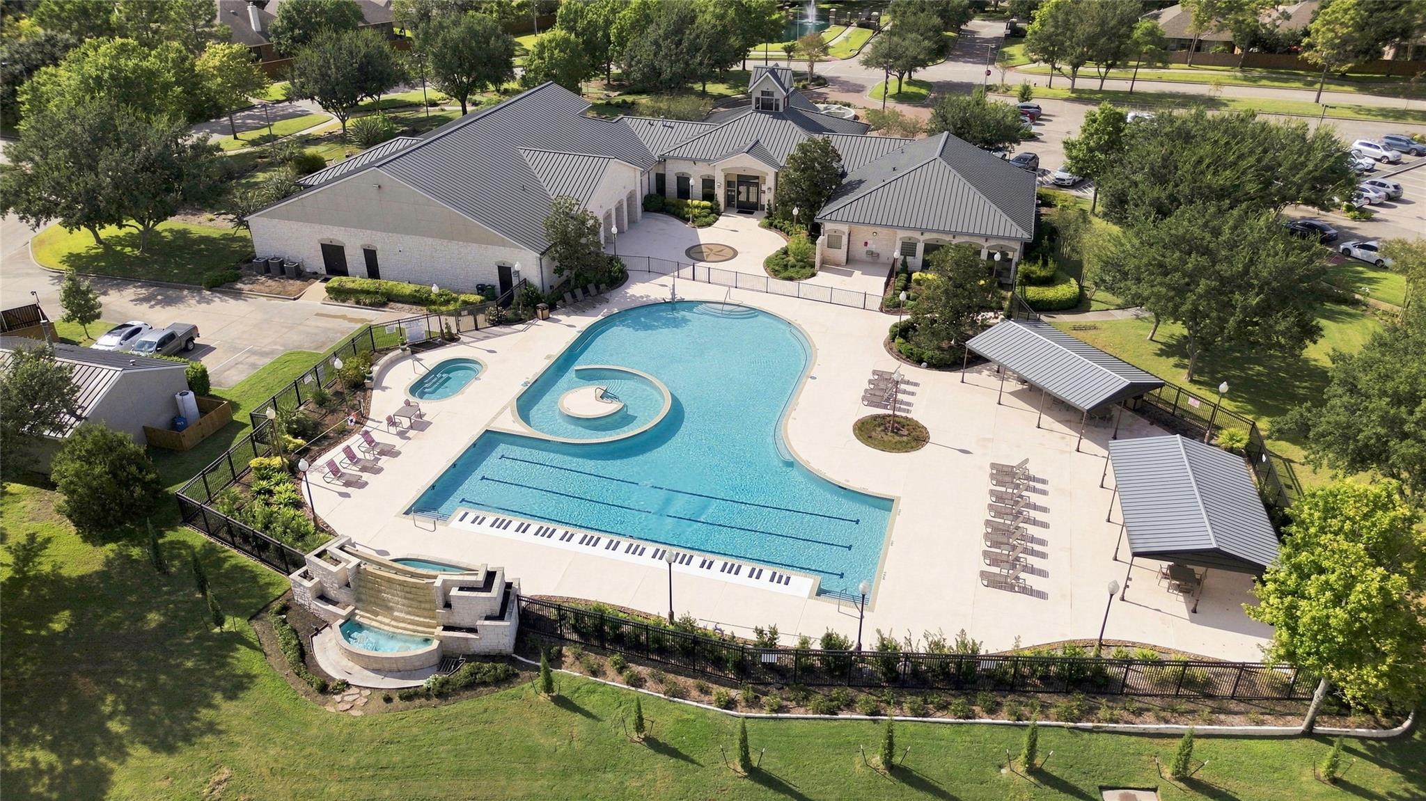 Aerial view of a community pool with a circular wading feature and clubhouse.