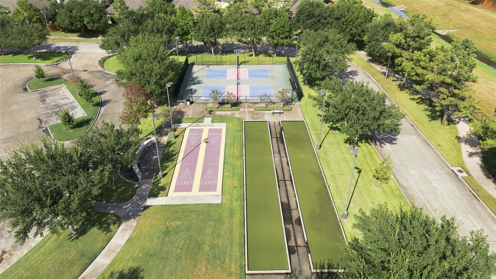 Aerial view of community recreation courts and bocce lanes surrounded by trees.