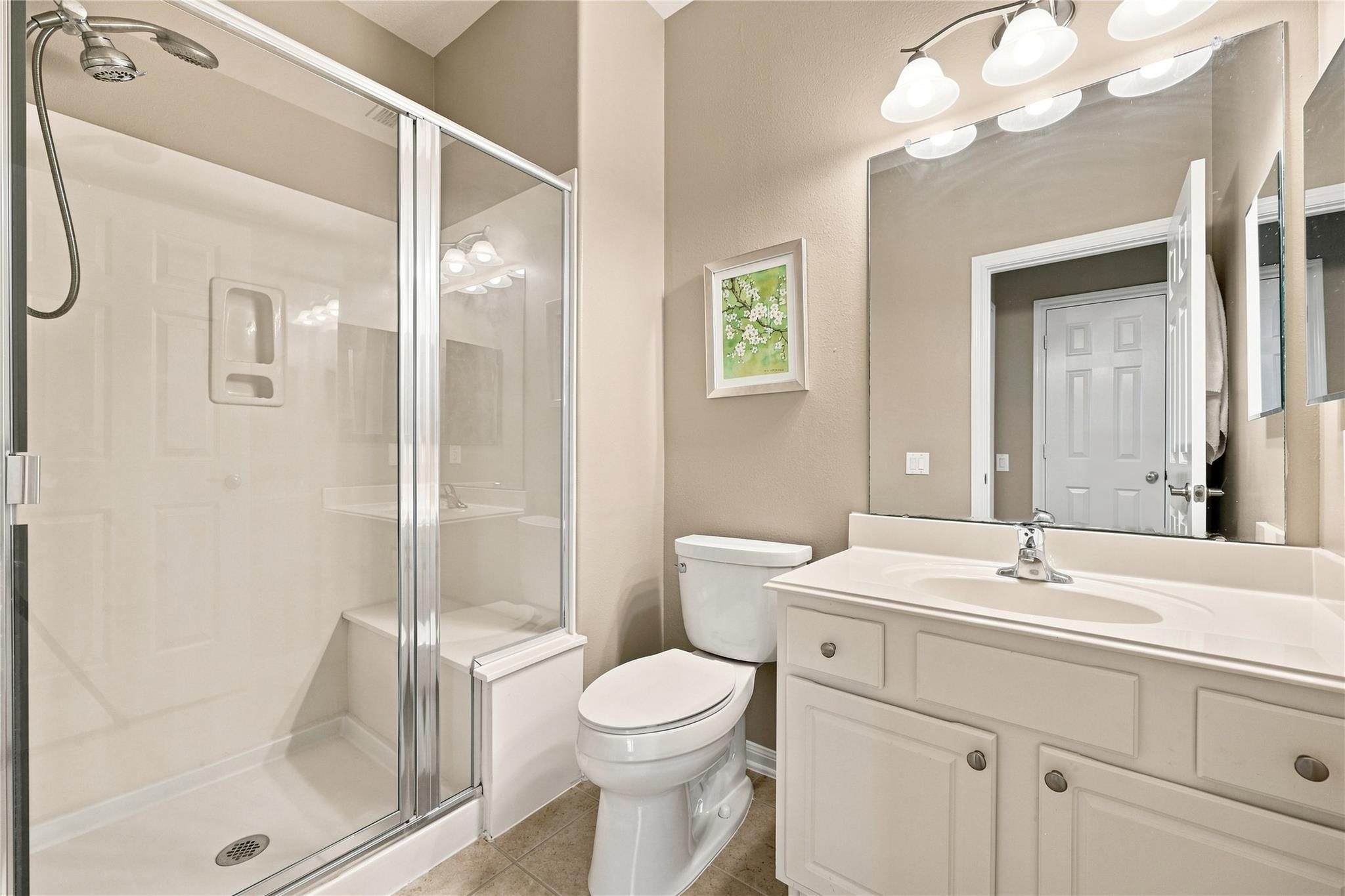 Bathroom with a glass-enclosed shower, white vanity, and large mirror.