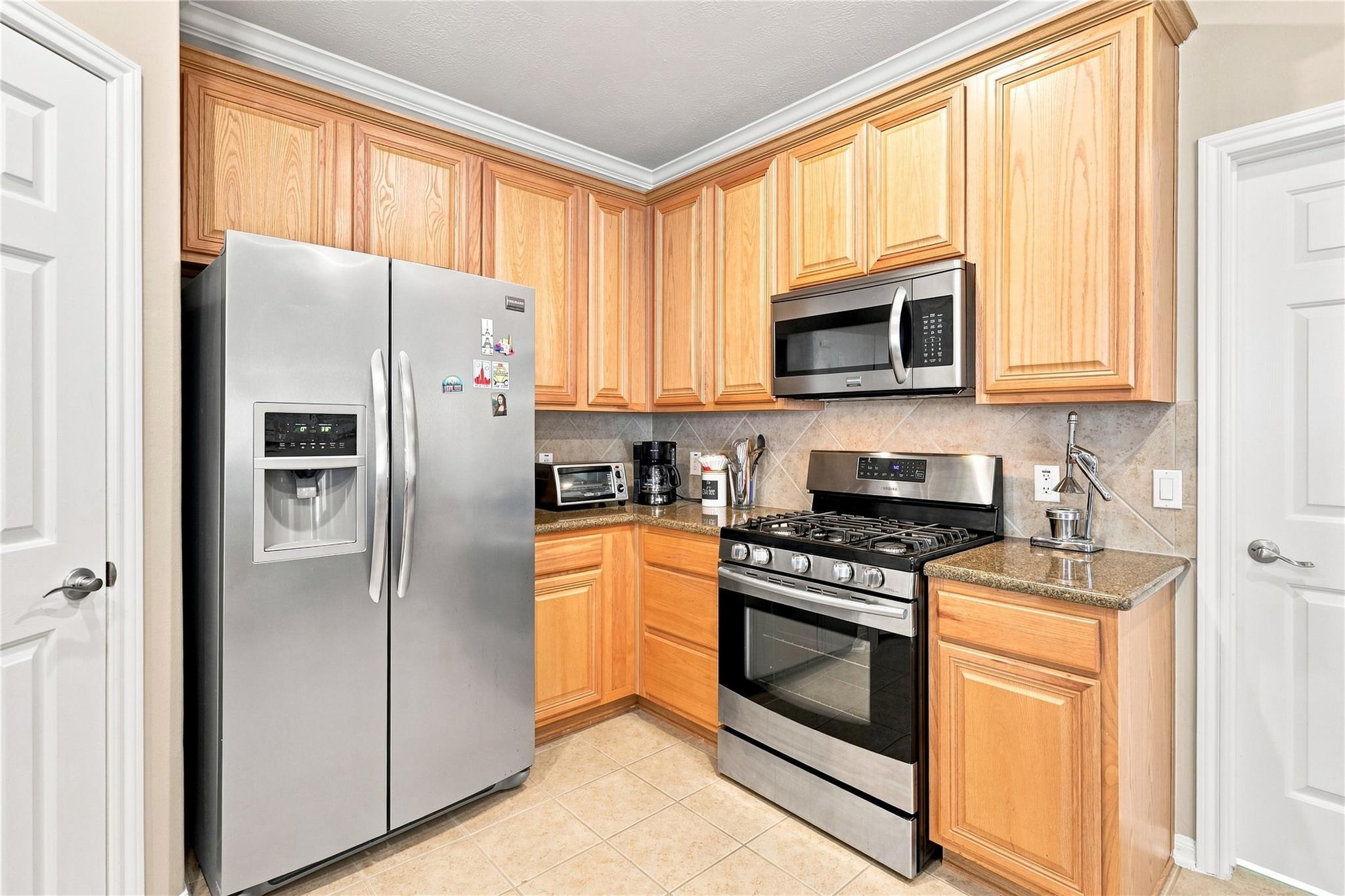 Kitchen with honey-colored wood cabinets, granite counters, and stainless steel appliances.