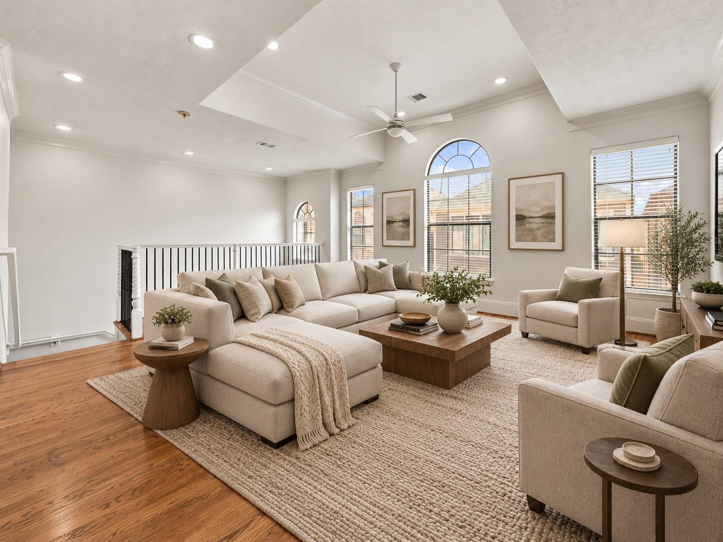 Living room with a vaulted ceiling, arched windows, and a neutral sectional on a large textured rug.