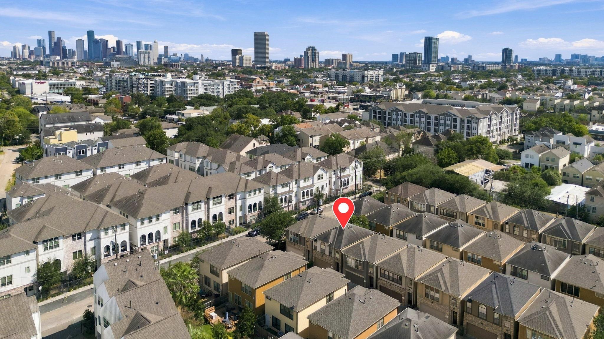 Aerial view of Houston townhomes with downtown skyline and a red pin marking the property.