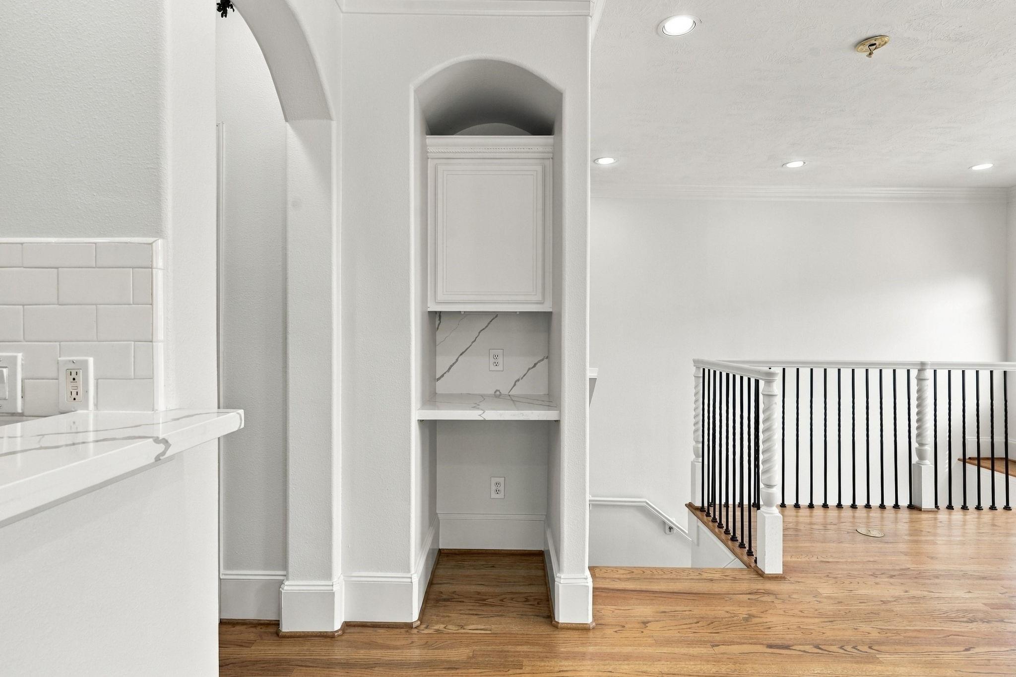 Interior with a marble-look counter, built-in niche, and hardwood landing with a black-and-white railing.