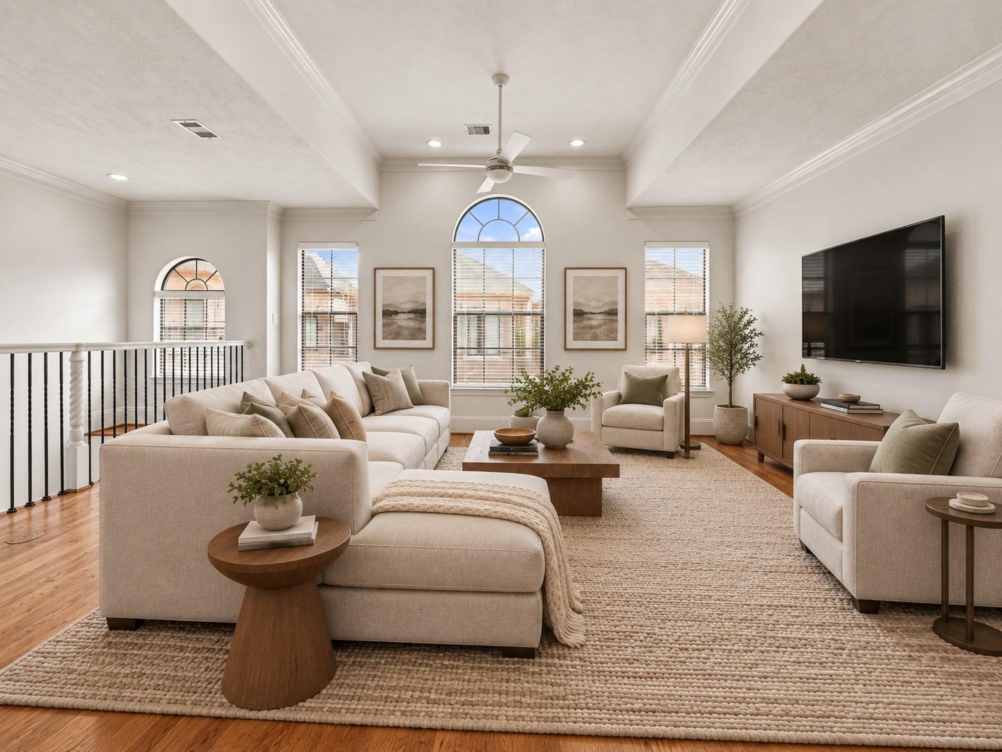 Living room with vaulted ceiling, arched windows, and neutral furnishings.