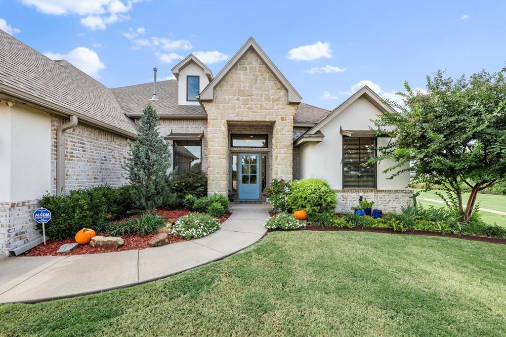 Stone-and-stucco house with a blue front door, landscaped garden beds, and a curved walkway.