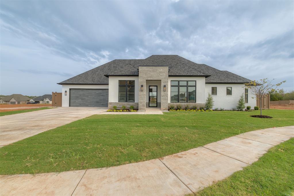 Modern single-story home with a stone-framed entry, large windows, and an attached garage.