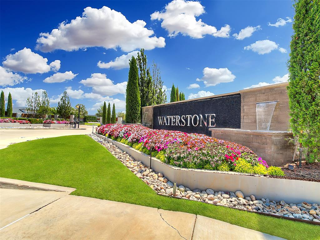 Waterstone entrance sign beside colorful flower beds and a neatly trimmed lawn.