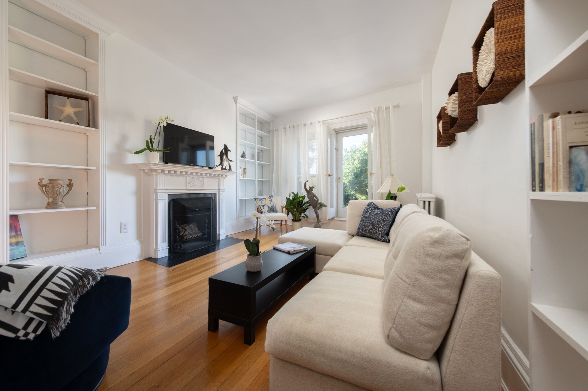 Living room with a cream sectional, white fireplace and built-ins, and hardwood floors.