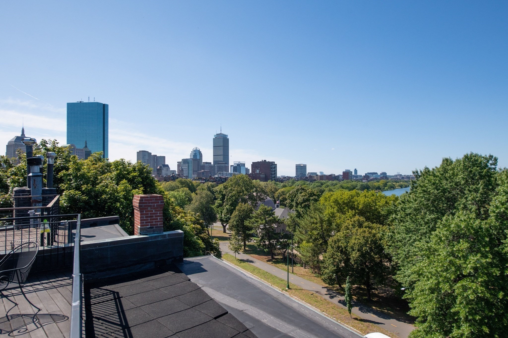 Rooftop terrace overlooking Boston’s skyline, leafy parkland, and the river.