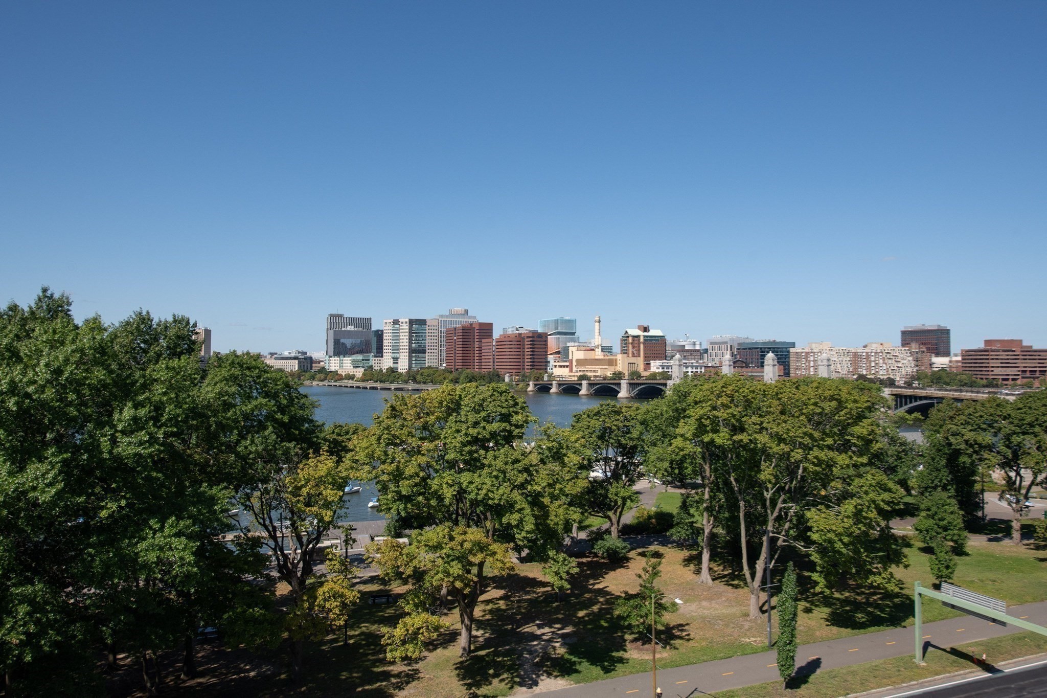 Riverside park and Charles River with an arched bridge and Boston skyline beyond.
