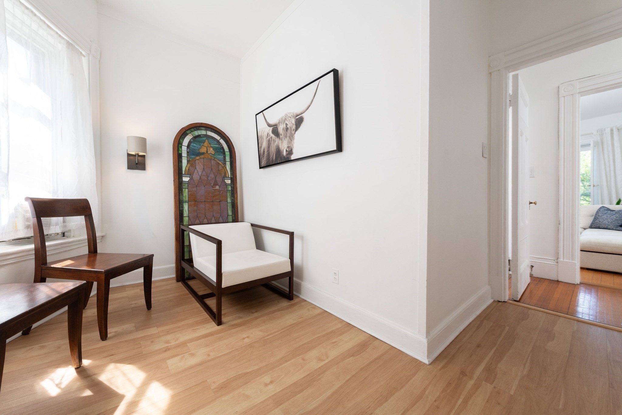 Sitting area with dark wood chairs, a stained-glass panel, and a doorway to the adjoining living room.