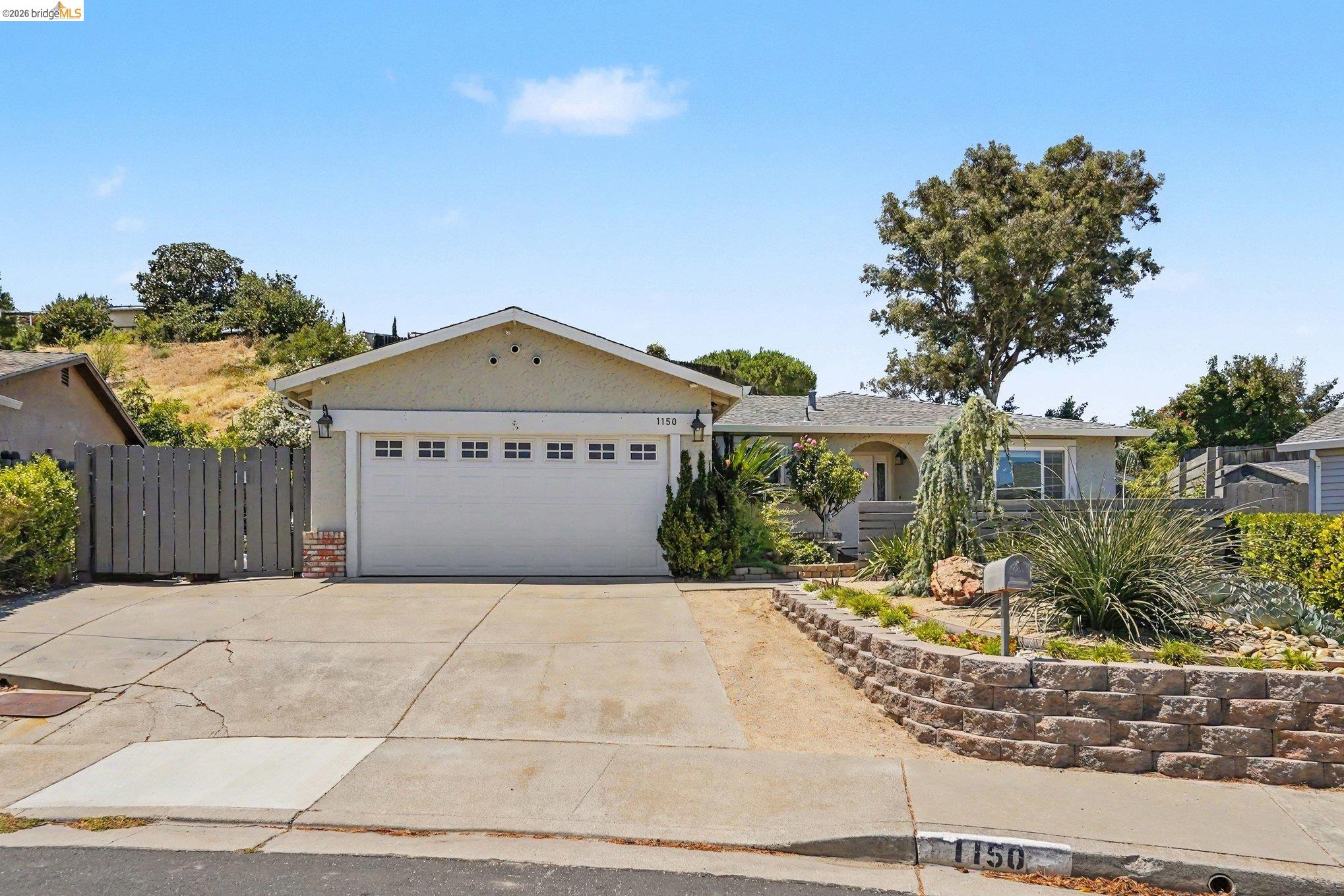 Single-story home with a broad white garage door, arched entry, and landscaped front yard.