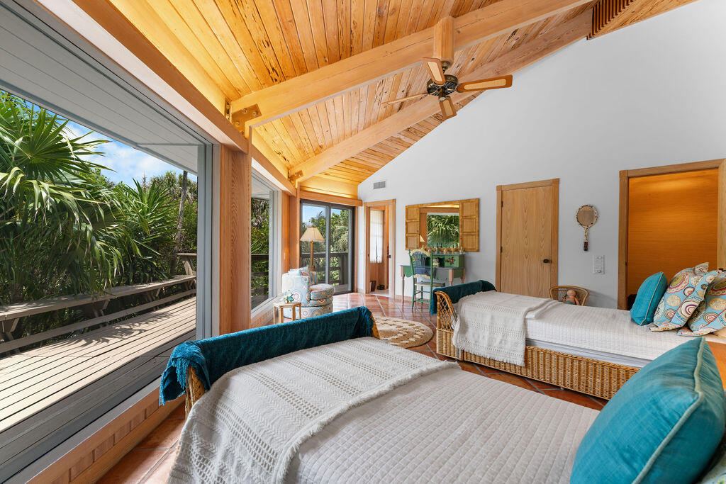 Bedroom with twin wicker beds, a vaulted wood ceiling, and sliding doors to a tropical deck.