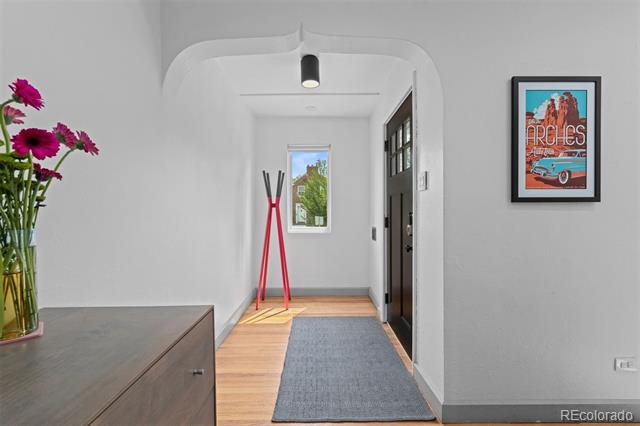 Entry hall with wood flooring, gray runner, red coat stand, and framed Colorado poster.