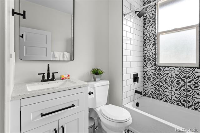 Bathroom with a white vanity, bathtub, and distinctive black-and-white patterned tile.
