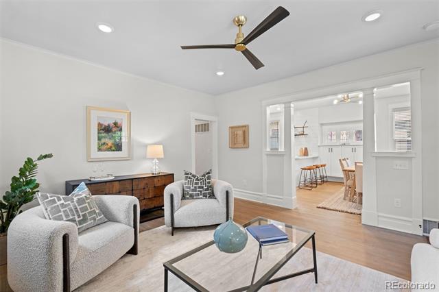 Living room with two gray armchairs, a glass coffee table, and an open view into the kitchen.