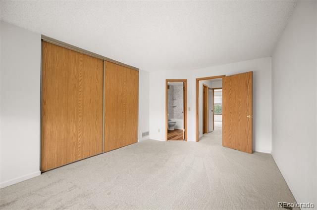 Vacant bedroom with wide wood sliding closet doors and open doors to the bathroom and hallway.