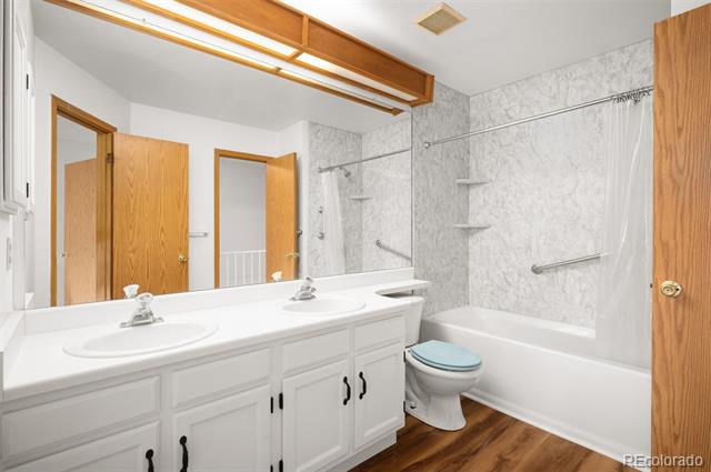 Bathroom with a double vanity, white cabinetry, and a bathtub with a marble-look surround.